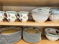 Stacked mugs, bowls and plates on shelf showing pattern and quantity grouping