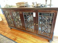 Front view of four-door glass-paneled Woodbridge sideboard with brass knobs and bun feet