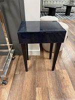 Front angled view of black accent table showing glass top and legs