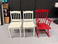 Front view of two white side chairs and one red rocking chair