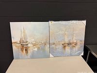Two 24" square canvas prints, one fully wrapped in original plastic, showing sailboat artwork