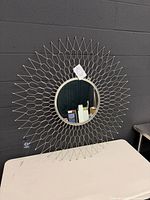 Front view of silver sunburst mirror standing on table