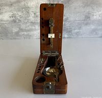 Closed wooden case opened to show balance beam, pan, weight recesses