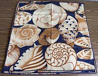 Full view of stacked placemats displaying seashell pattern