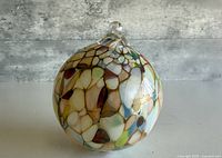 Front view showing multicolour mosaic surface and hanging loop