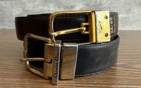 Both belts coiled showing buckles and leather colors