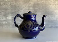 Front view showing entire cobalt blue teapot with silver overlay