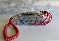 Side profile of clear phone showing red cord and internal components