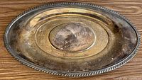 Top view of oval silver-plated tray with decorative rim and tarnish visible