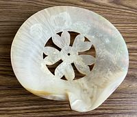 Front view of mother of pearl dish showing floral cut-out and nacre finish
