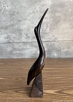 front view of carved wooden crane on base