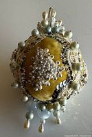 Top view of yellow satin ornament showing pearl and sequin embellishments and hanging loop