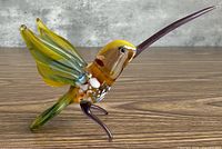 Side view of entire blown glass hummingbird figurine on tabletop
