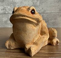 Front view of tan frog figurine with dark eyes