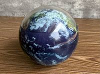Front view of spherical Earth globe with clear top half and realistic imagery