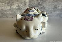 Front angled view of porcelain sleeping cat with floral motifs