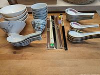 Assorted bowls, chopsticks and soup spoons laid out on table