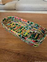 Top angled view of multicolor woven recycled wrapper oval basket