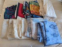 Stack of patterned and solid shower curtains folded on bed