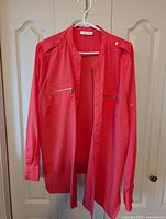 Full frontal view of salmon Calvin Klein blouse on hanger showing overall style, sleeves, and length