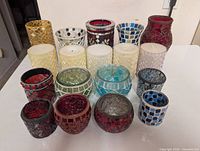 Group shot of 18 assorted mosaic glass candle holders, some with candles