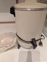 Off-white electric coffee urn with filters beside