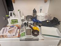 Overview of all cooking items on counter including spiralizer, graters, measuring cups, baking dish, oven mitts