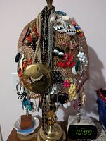 Lamp base with mesh holder densely covered in earrings, necklaces and chains