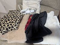 Group of five folded blankets in assorted colors and patterns with heating pad on top