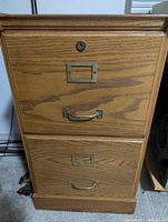 Front view of one wooden two-drawer filing cabinet showing metal hardware