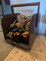 Wooden firewood holder loaded with packaged fire logs, view of exterior and handle