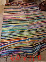 Full view of large multicoloured rag rug laid flat showing overall pattern and wear