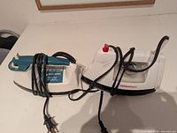 Both irons side by side showing overall condition, cords and plugs visible