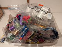 Basket with ribbon rolls, metallic threads, beads and other craft items