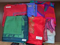Group of eight folded Thai silk scarves showing labels and variety of colors