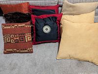 Group of six pillows in varied colours and textures on carpet