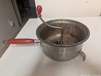 Side view Foley food mill showing red handle, crank, spout