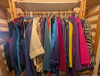 Row of assorted women’s tops and jackets on hangers, multiple colors