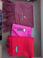 Three scarves stacked showing colors, fringe, tags visible