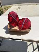 Pair of circular red LED tail lamps resting on box