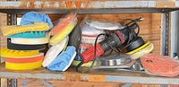 Polisher with cord, installed yellow pad, multiple foam and wool pads stacked on shelf
