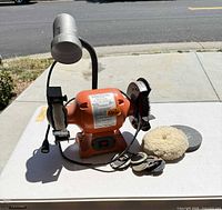 Full view of bench grinder with lamp and accessories on table