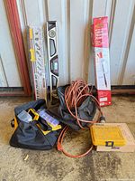 Group shot showing levels, transfer pump, extension cord, tool bag, cardboard box and plastic organizers