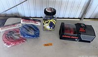 Overview of compressor, two packaged cords, jar of assorted cords on table