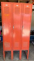 Front view of orange three-door steel locker cabinet on legs