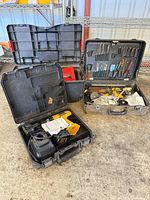 Wide view of three tool cases including open DeWALT drill case, briefcase tool kit, and additional toolbox