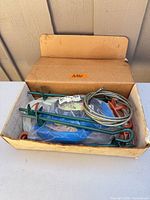 Box containing tie-down components including anchors, cable and straps