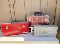 Three storage units: red metal toolbox, Milwaukee organizer, silver Craftsman toolbox with regulator
