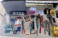 Overall view of tools and supplies on table including torque wrench case, cloths, repair kit, demagnetizer, zip ties, pliers, wrenches, screwdrivers, gloves