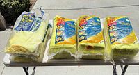 Four plastic-wrapped packs of yellow microfiber towels on table